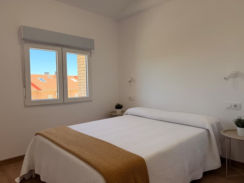 Dormitorio de la Casa A con cama de matrimonio y manta mostaza
