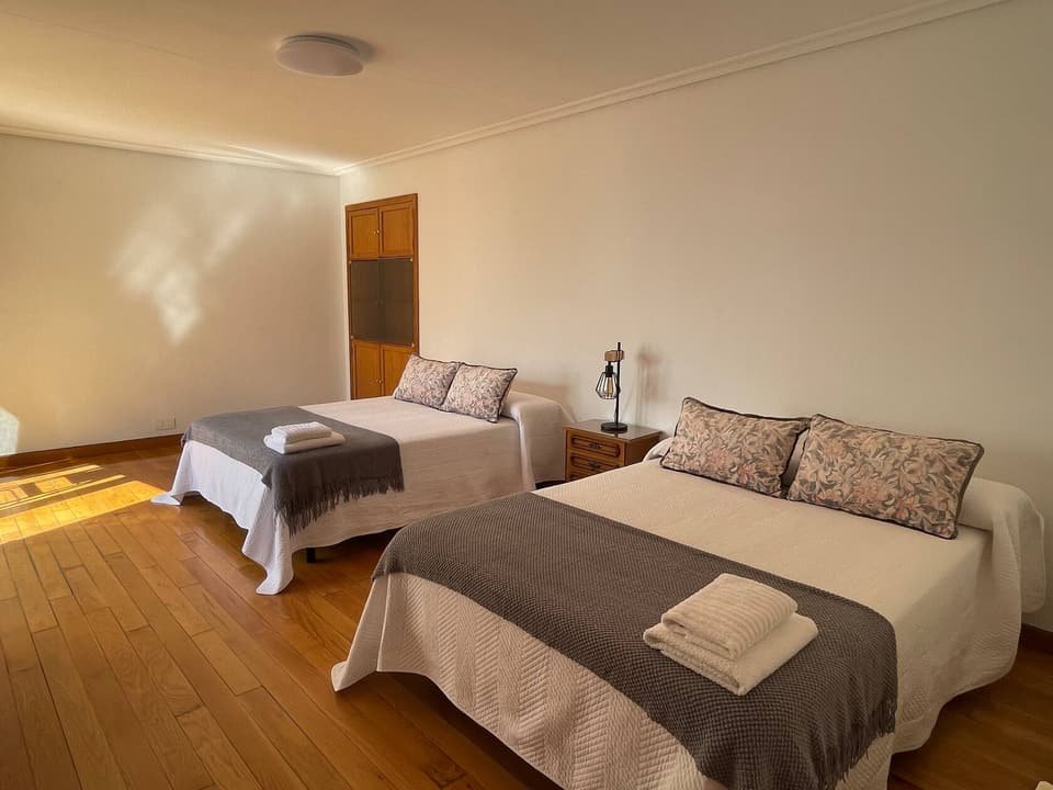 Dormitorio amplio de la Casa B con dos camas y suelo de parqué