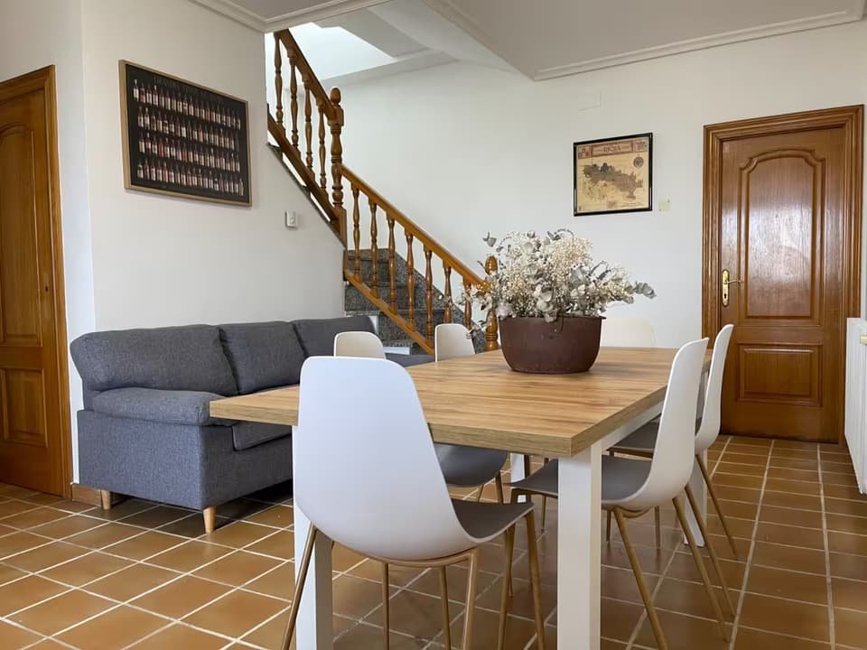 Salón comedor de la Casa B con sofá y escalera de madera